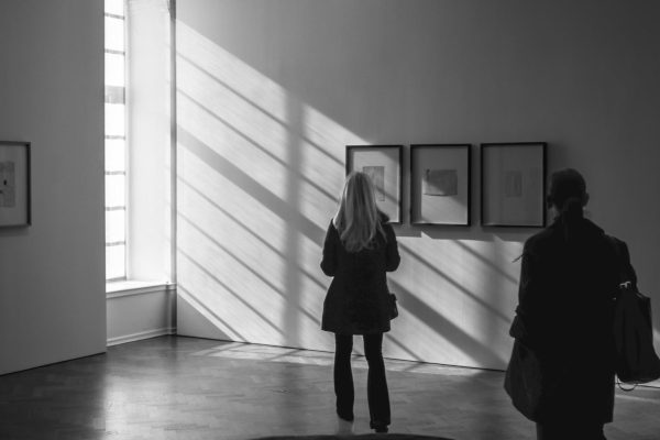 Donna osserva opere in galleria con ombre drammatiche, bianco e nero.
