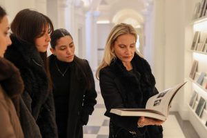 La profesora Virginia Damtsa muestra un libro de arte abierto a estudiantes.