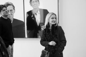 La profesora Virginia Damtsa y un estudiante frente a retratos a gran escala.