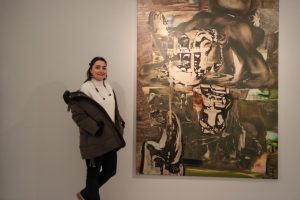 Mujer junto a una gran pintura abstracta en una galería.