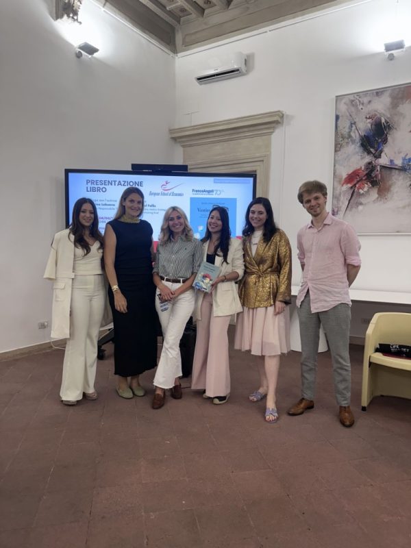 Group photo of six professionals posing in front of a presentation screen during the book launch of 
