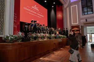 Graduates line up on stage at Town Hall by Bottaccio as family and friends capture the moment — ESE Graduation Ceremony, 4th July 2026.