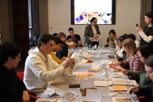 Smiling students working at a long table during a workshop, with an ESE Business School banner behind them.