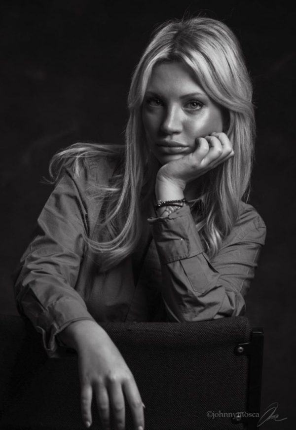 Black and white portrait of Diletta resting her chin on her hand while leaning on a chair.